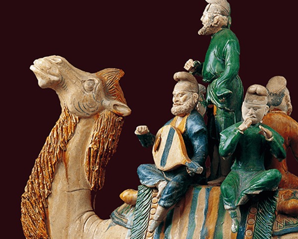 Colorful sculpture of three musicians riding a camel.